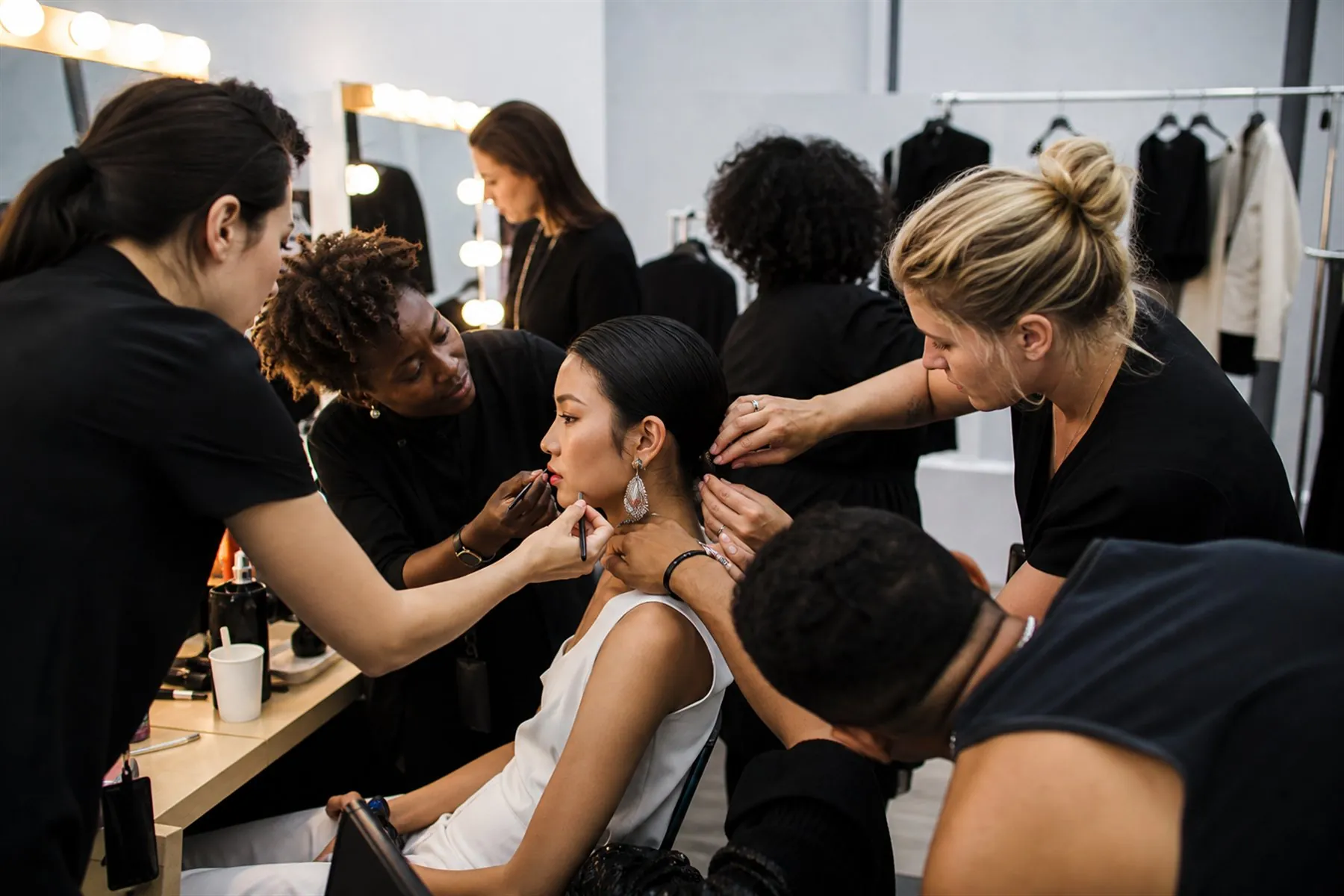 Visuel éditorial : Équipe beauté préparant une silhouette en coulisses avant une présentation de mode